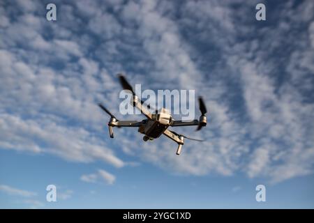 Photograph of a DJI drone centered within the frame, flying in the sky with captured propeller momentum. Shot at golden hour with a blurred background Stock Photo