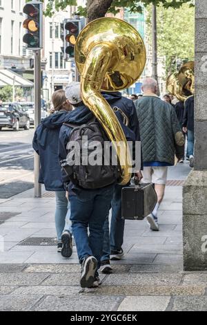 A man with a sousaphone on his back walking down in Dublin, Ireland. Stock Photo