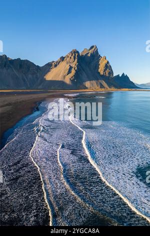 Aerial view of Vestrahorn mountain and the coastal road winding through ...