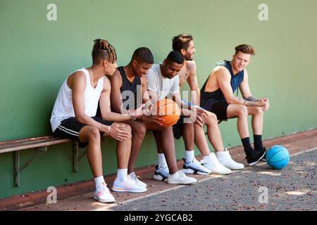 Bench, basketball and people on court for break, fitness exercise and wellness in sports match. Relax, athletes or group of healthy players resting Stock Photo