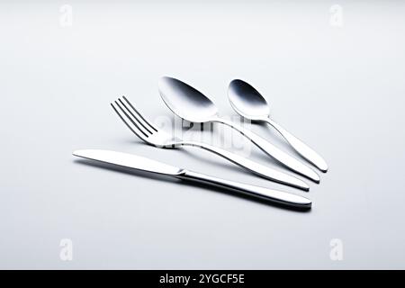 Silver colored cutlery such spoons, forks, knives, cups and plates photographed against a white background Stock Photo