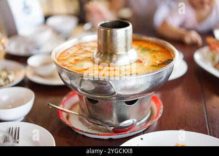 Tom Yum Kung Nam Khon or Thai creamy hot and spicy herbal soup with shrimp served in Thai style hot pot at the famous local restaurant. Stock Photo