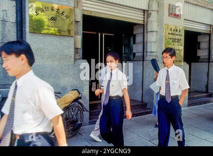 China, Shanghai, Students in uniform passing stock exchange building in the financial district. Stock Photo