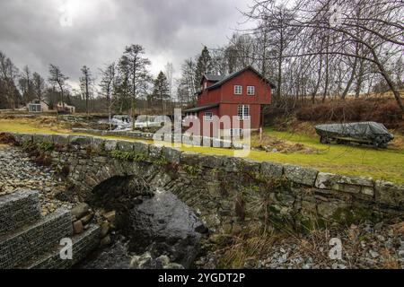 Beautiful red Swedish house. Former watermill on a river with a small waterfall. Sunset in a beautiful landscape with a wooden house in Sweden, Scandi Stock Photo