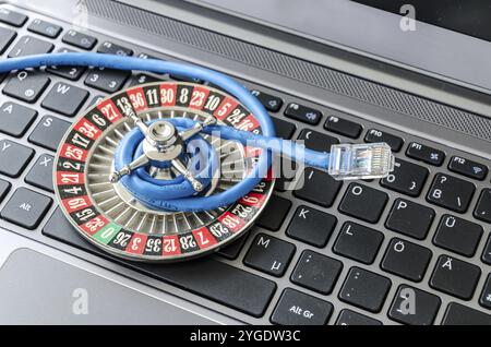 Roulette wheel and internet cable lying on computer keyboard symbolizing data encryption Stock Photo