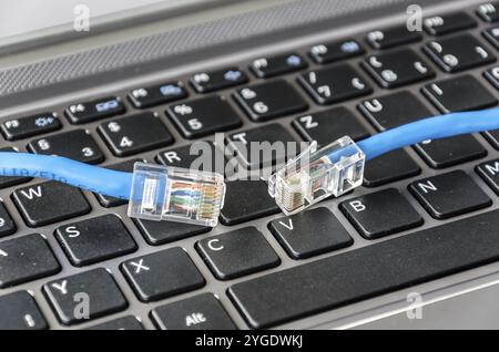 Two internet cables on a computer keyboard symbolizing connectivity issues Stock Photo