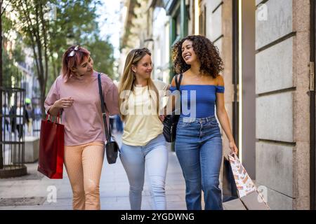 Happy three diverse women walking and shopping in the city together embraced Stock Photo