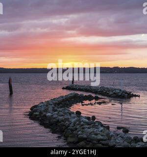 Breakwater rocks at the Baltic Sea during dramatic colourful sunset Stock Photo