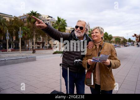 Happy Caucasian senior tourist couple using a travel map on the city, enjoying their holidays. Stock Photo