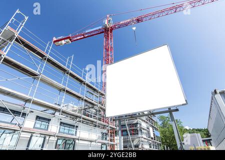 Blank billboard on a construction site with unfinished building, scaffolding and crane Stock Photo