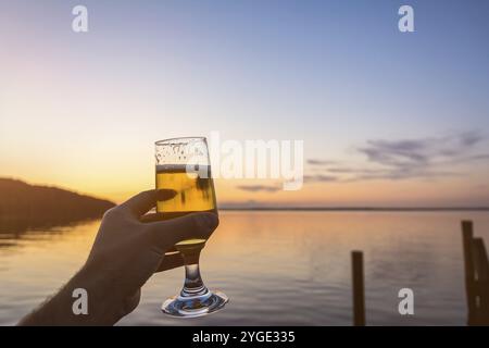 Having a fresh cold beer at the seashore during a beautiful colorful sunset Stock Photo