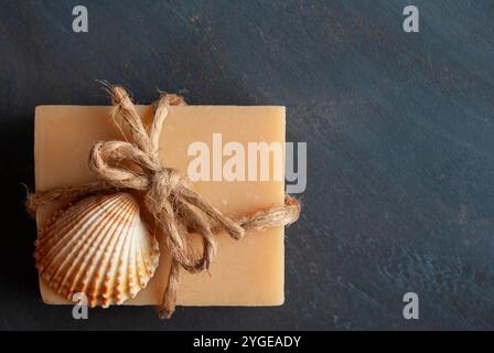 Homemade lavender soap with a decorative bow and sea shells on a dark background, creating a soothing, natural scene. Stock Photo