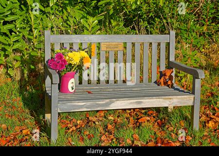 Pluscarden Abbey a Catholic Benedictine monastery near Elgin Scotland Commemorative Seat with flowers and leaves in autumn sunshine Stock Photo