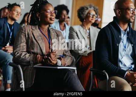 Diverse group of professionals at a business conference, focused on a presentation. Colleagues sitting attentively in an audience. Stock Photo
