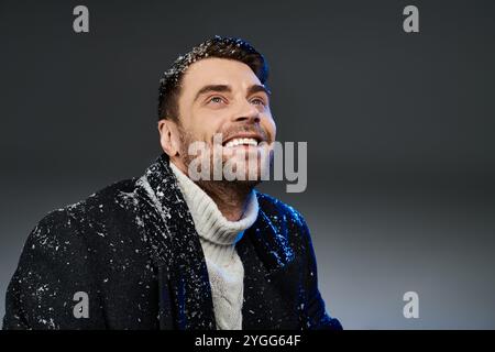 A charming young man enjoys a moment of happiness as snowflakes fall around him. Stock Photo