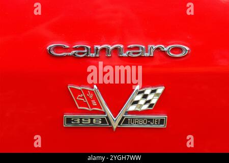 Close up of a 1967 - 1969 first generation Chevrolet Camaro 396 RS turbo-jet chrome front fender badge gleaming on scarlet red paintwork. Stock Photo