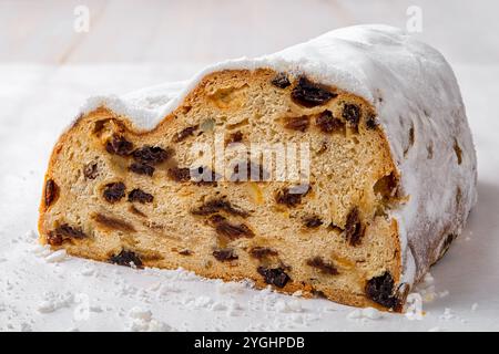 Stollen cake-like loaf cut in half closeup. Traditional German Christmas bread of dried fruits, nuts and spices coated with powdered sugar on a table. Stock Photo