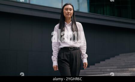Confident Asian Korean woman businesswoman going steps walking successful business female entrepreneur leader boss ceo lawyer manager girl smile Stock Photo