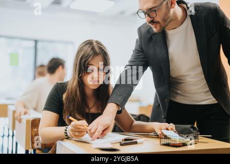 Teacher assisting high school student during classroom lesson Stock Photo