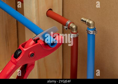 Cutting and installing PEX plastic water supply plumbing pipe in wall of house. Home repair, maintenance and remodeling concept. Stock Photo