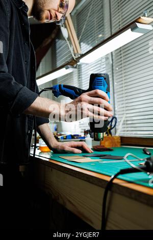 The hands of the master sew handmade leather products. Men's hands connect the parts, creating quality leather accessories. Working process in a leath Stock Photo