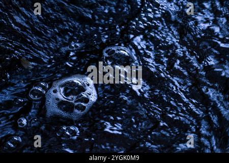 Air bubbles on the water surface of a stream, blue hour, Germany Stock Photo