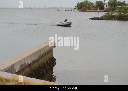 Editorial Use Only,  November 7, 2024. Gulfport, FL, USA. Leading lines sea wall view across outlet to Boca Ciega Bay to Small motor boat heading in t Stock Photo