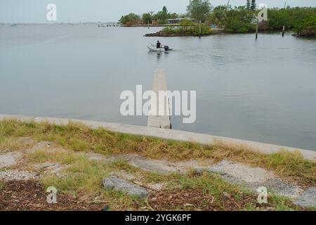 Editorial Use Only,  November 7, 2024. Gulfport, FL, USA. Leading lines sea wall view across outlet to Boca Ciega Bay to Small motor boat heading out Stock Photo