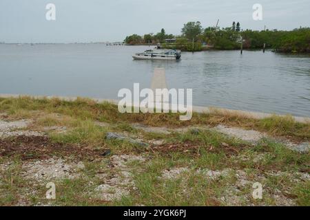 Editorial Use Only,  November 7, 2024. Gulfport, FL, USA. Leading lines sea wall view across outlet to Boca Ciega Bay to Small motor boat heading out Stock Photo