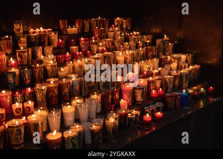 Candles with religious images, casting a warm glow in a dark setting at
