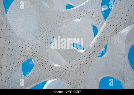A dynamic white structure appears as an optical illusion against a blue sky. Stock Photo