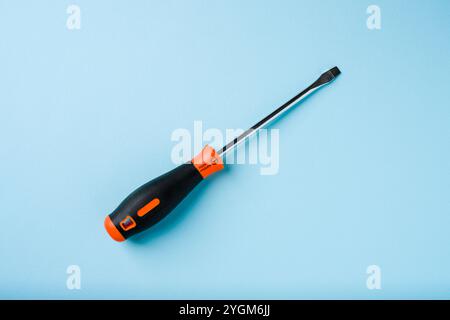 Flathead screwdriver with orange and black handle on blue background Stock Photo