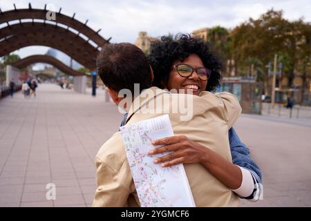 Multiracial couple meeting during holidays and hugging outside on the street. Stock Photo