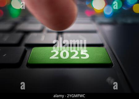 Keyboard with text 2025 year and finger pushing the enter button. Color button on the gray silver keyboard of modern ultrabook. caption on the button. Stock Photo