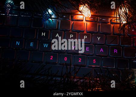laptop keyboard surrounded by lights of a Christmas garland. Christmas decorations on the computer. technology and christmas concept. HAPPY NEW 2025 Y Stock Photo