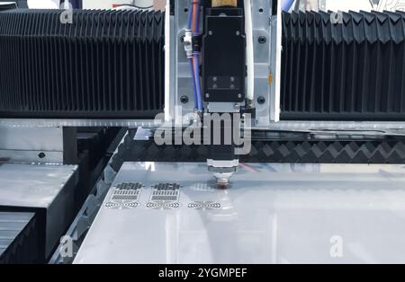 CNC fiber laser cutting machine cutting metal sheet with flying sparks. Industrial metalworking machinery Stock Photo