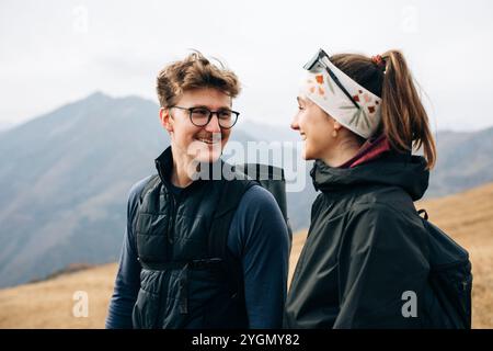 Couple smiling on a mountain, wearing hiking gear Stock Photo