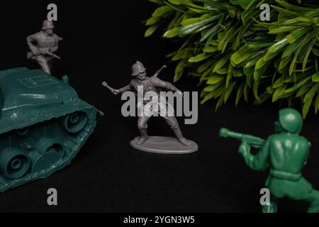 Fighting toy soldiers and tank on a black background. International Day for Preventing the Exploitation of the Environment in War and Armed Conflict. Stock Photo