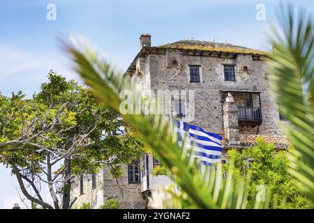 Ancient Ouranoupolis Tower on Athos peninsula in Halkidiki, flag of Greece. View through the palm leaves Stock Photo