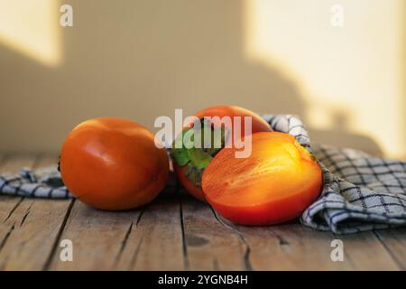 Fresh ripe persimmon fruits on wooden table in sunlight. Closeup. Stock Photo