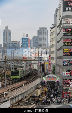 Moving train on the railway tracks next to the Ameyoko shopping street during the day in the Ueno neighbourhood in the Taito district of Tokyo city in Stock Photo