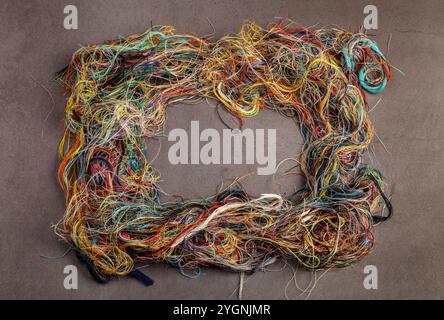 Colorful tangled threads on dark gray background Stock Photo