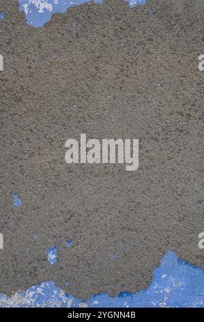 Texture of old and crumbling gray plaster revealing a layer of  an even older blue plaster. Stock Photo
