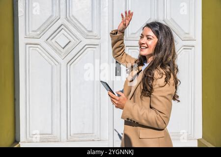 Young businesswoman using smart phone while waiting in formalwear on the city street for colleagues to go to lunch break. Fashionable business female Stock Photo