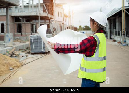 Engineers holding blueprint project working outdoors building side with blueprints on a worksite, Engineering and architecture concept, Engineer worki Stock Photo
