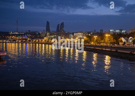 Baku, Azerbaijan. View looking towards the Flame towers at dusk.  Baku is located on the western shore of the Caspian SeaThe Flame Towers, near Highland Park, Baku, Azerbaijan, serve as an architectural landmark that reflect Azerbaijan's oil heritage while projecting a forward-looking identity, Stock Photo