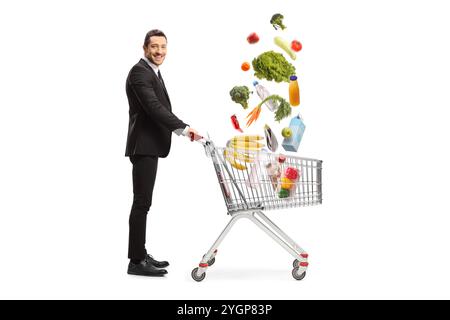 Businessman with groceries falling in a shopping cart isolated on white bacakground Stock Photo