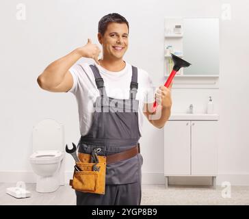 Man from a plumbing service using a plunger for a clogged toilet in a bathroom Stock Photo