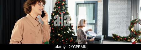 A group of young coworkers enjoys a festive Christmas atmosphere while working in the office. Stock Photo