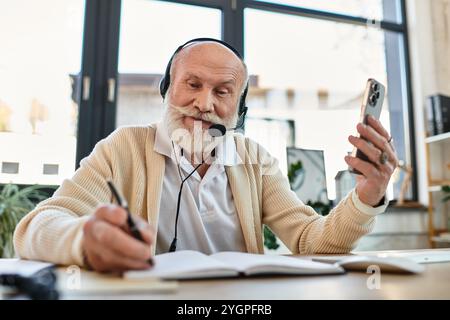 A senior businessman wearing smart casual clothes connects with colleagues, taking notes while working. Stock Photo